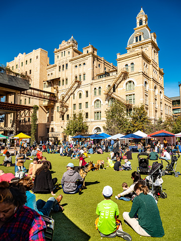 San Antonio, Texas, USA- January 31, 2020. Exterior of Emma Hotel, located on the grounds of Pearl Brewery. Last weekend in January. People enjoying beautiful day on the lawn in front of the hotel. Farmers market with visitors. Families and their pets soaking the sun.
